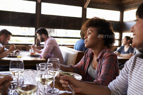 Two female friends at a girls’ lunch in a busy restaurant