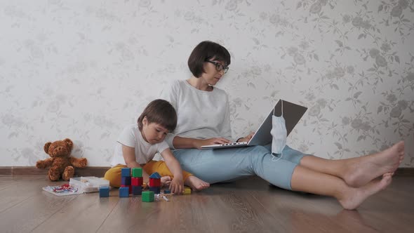 Mom and Son Sit at Home Quarantine Because of Coronavirus COVID19. Mother Remote Works with Laptop alt