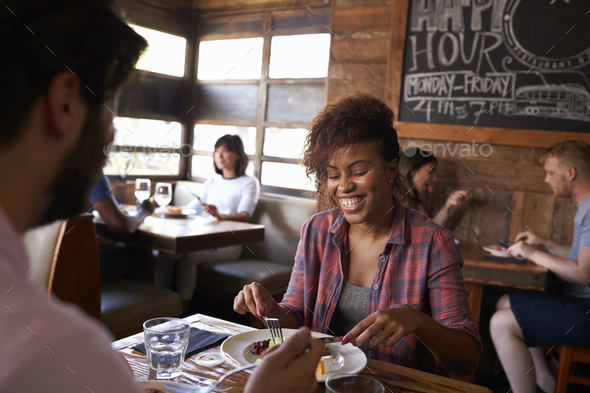 Mixed race couple having lunch in busy restaurant, close up