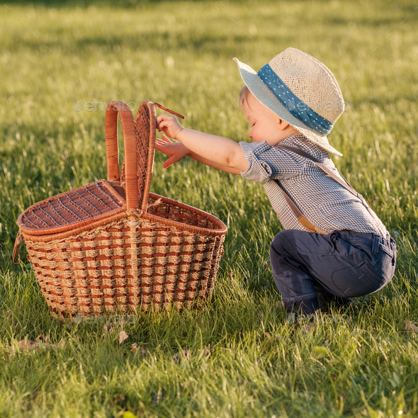 Toddler child outdoors. One year old baby boy wearing straw hat looking