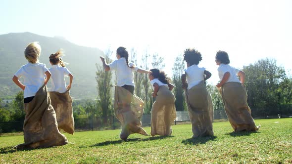 Children playing a sack race in park alt