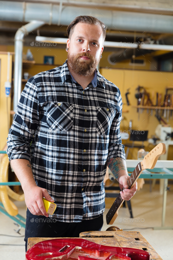Carpenter work on a wooden guitar neck in workshop Stock Photo by kjekol