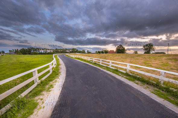 Curved road with white fences leading to village - Stock Photo - Images