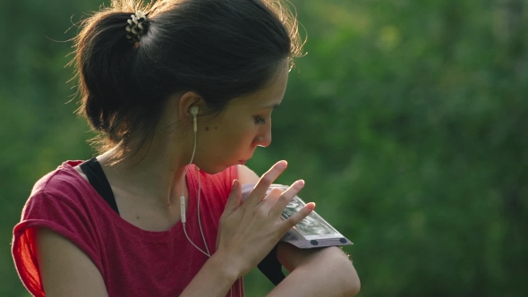 Young Woman Listening To Music with Earphones on Smart Phone App for Fitness Motivation. Athlete