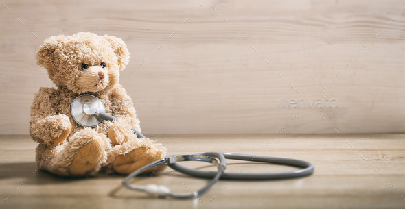 Teddy bear and a stethoscope on a wooden floor