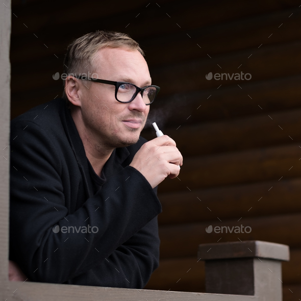 Caucasian man smoking modern hybrid cigarette device outdoor - Stock Photo - Images