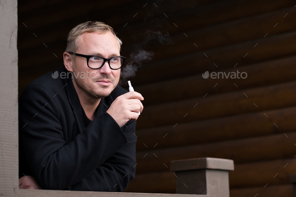 Caucasian man smoking modern hybrid cigarette device outdoor - Stock Photo - Images
