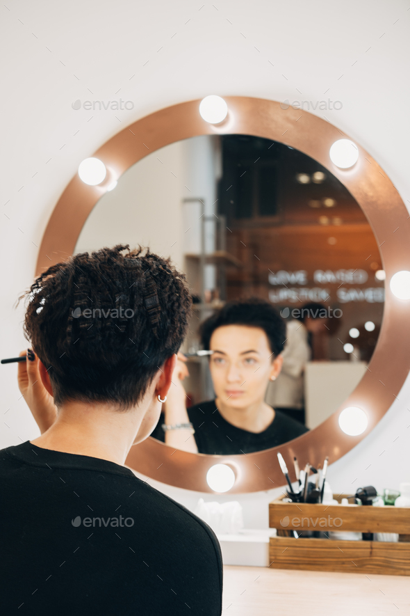 Attractive woman at the mirror in beauty studio - Stock Photo - Images