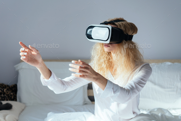 Girl sitting on a bed with VR headset Stock Photo by simbiothy | PhotoDune