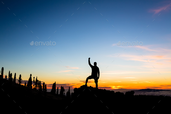 Man celebrating sunset in mountains with arms outstretched