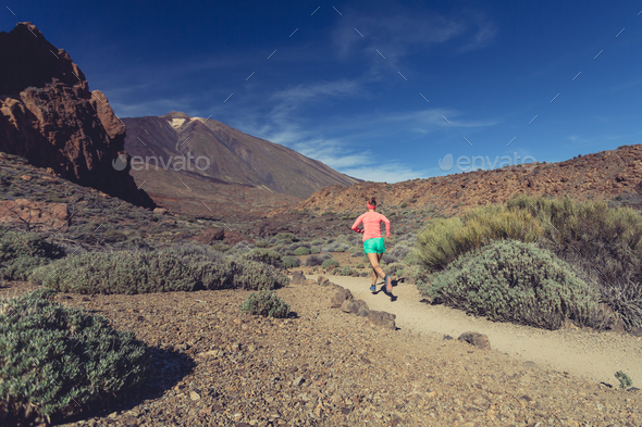 Woman trail running in mountains on sunny day