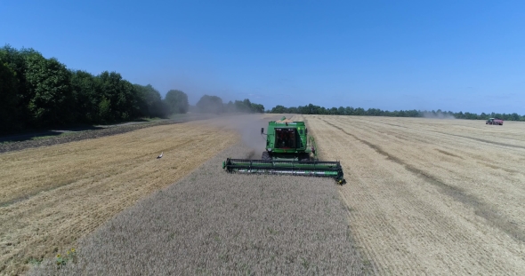 Aerial Front View of Driving Harvesting of Wheat By Modern Green Combine on the Field of Wheat alt