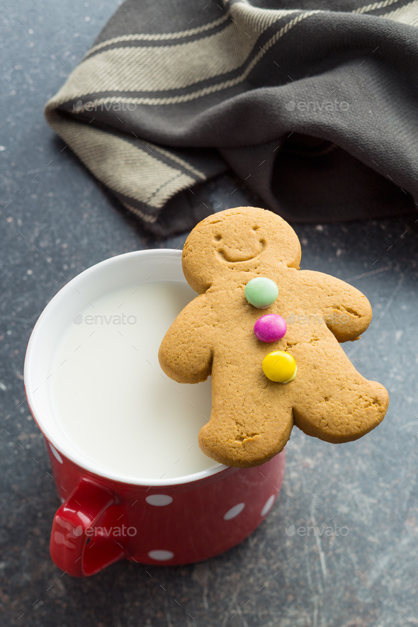 Two gingerbread man and mug of milk.