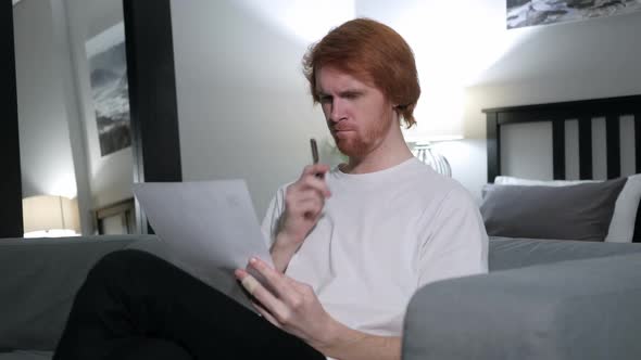 Penisve Redhead Man Reading Letter Sitting on Sofa alt