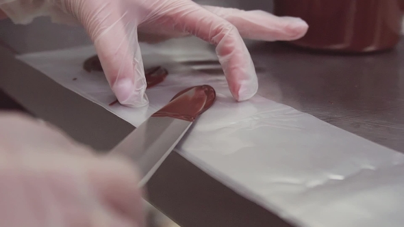 Female Pastry Chef Hands in Plastic Gloves Puts Chocolate on Cooking Strip