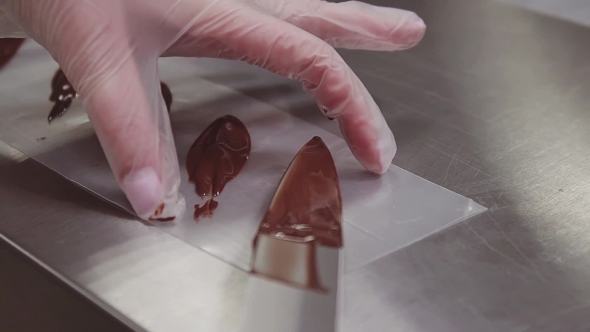 Woman Pastry Chef Hands in Plastic Gloves Puts Chocolate on Cooking Strip