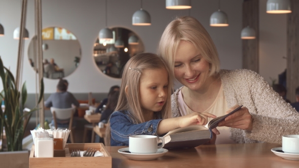 Mother and Daughter Read the Book at the Cafe alt