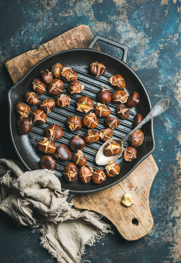Roasted chestnuts in grilling pan over dark blue background - Stock Photo - Images
