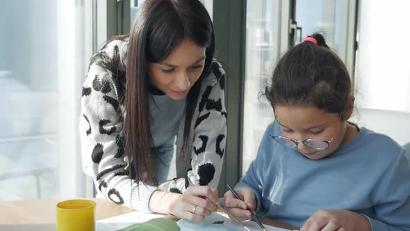 A Child and a Cute Teacher at a Drawing Lesson in a Modern Building Against the Background of a