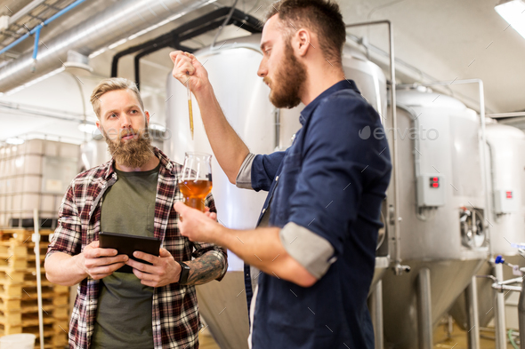 men with pipette testing craft beer at brewery - Stock Photo - Images