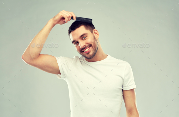 happy man brushing hair with comb over gray