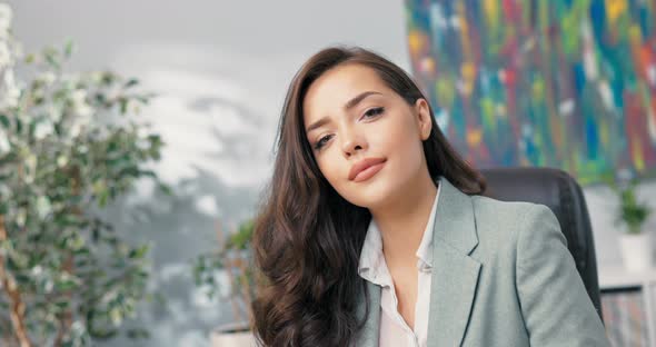 Close Up Shot of Attractive Corporate Office Employee Sitting at Desk Looks Into Camera Charming alt