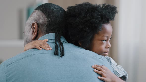 Happy African American Kid Girl Hugging Beloved Father Unrecognizable Adult Man Sits with Back to alt