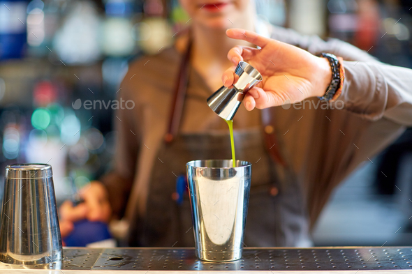 Bartender Hands Pouring Drink Into A Jigger To Prepare A Cocktail