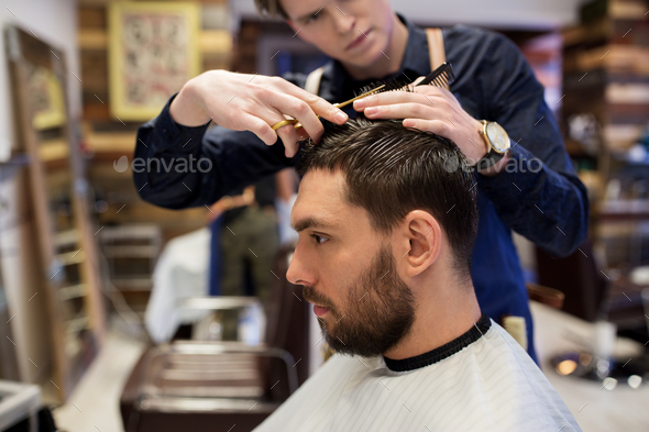 man and barber cutting hair at barbershop Stock Photo by dolgachov - A Person Who Cuts Hair Is Called