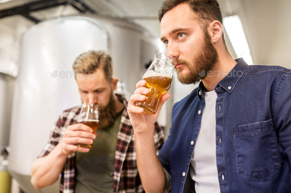 men drinking and testing craft beer at brewery - Stock Photo - Images