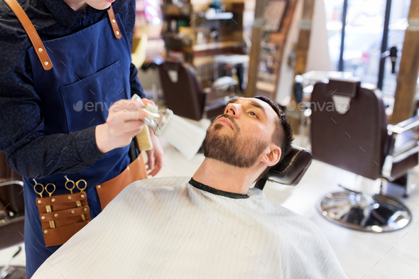 barber cleaning male face with brush at barbershop