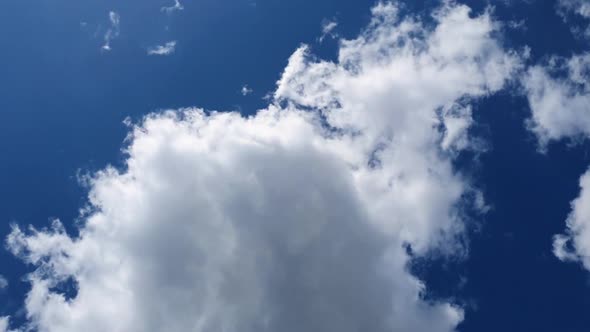 Low angle cloudscape time lapse. Fluffy clouds moving on the blue sky