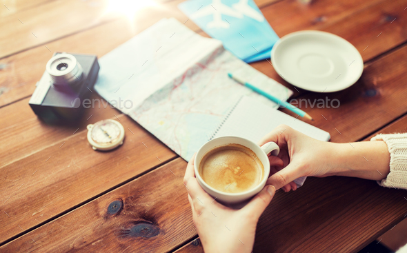 close up of hands with coffee cup and travel stuff