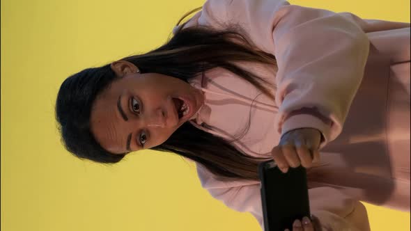 Pleasant-looking Black Girl Playing Games on Smartphone on Yellow Background. alt