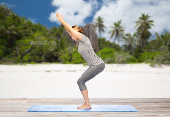woman doing yoga chair pose on beach