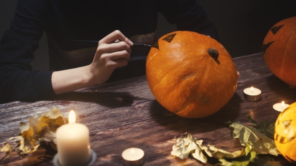 Young womanDrawing Eyes and Mouth on Halloween Pumpkin To Carve a Jack 'O' Lantern. The Winter