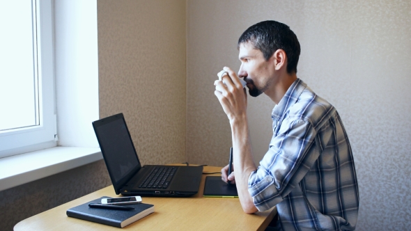 Man Working on Laptop and Drinking Coffee
