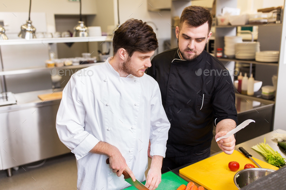 two chefs cooking food at restaurant kitchen
