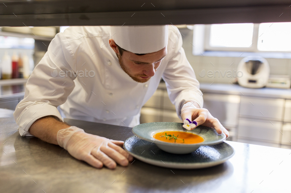 male chef decorating dish with pansy flower - Stock Photo - Images
