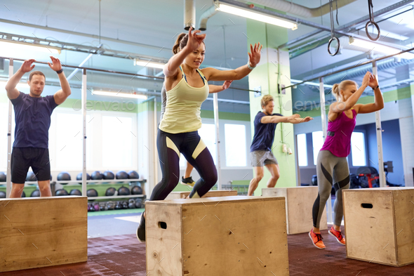 group of people doing box jumps exercise in gym