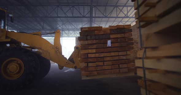 The work of a loader in a warehouse with a wooden board. Close-up loader lifts wooden boards.