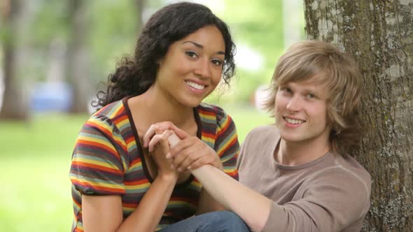 Portrait of couple sitting together by tree alt