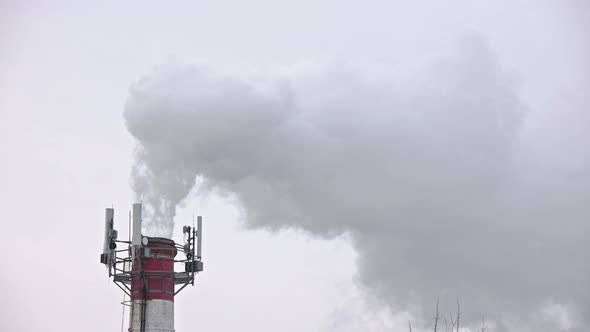 Thermal Power Station Pipe at Winter with Outgoing Smoke Steam and Isicles on Telecommunication alt