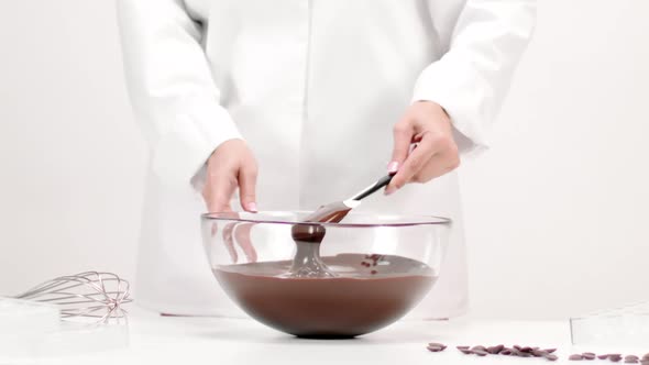 Chef Confectioner Mixing Melted Chocolate in Glass Bowl Slow Mo on White alt