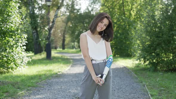 Girl with bionic prosthesis is walking on park Bionics Robotic-arm Hand prosthesis alt