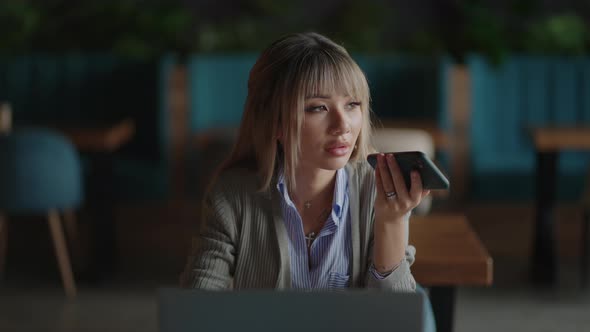 Asian Woman Talk on Cell Using Voice Assistant alt