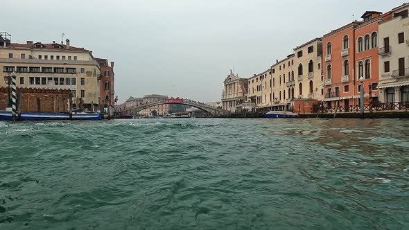 Water surface pov of Venice seen from ferry boat on Canal Grande with Ponte Degli Scalzi bridge in b alt