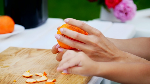 Summer, in the Garden, Female Hands Are Peeling an Orange From the Peel ...