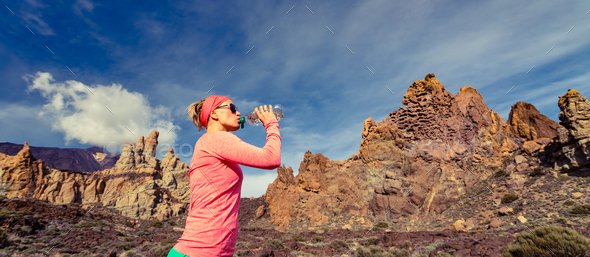 Woman trail runner drinking in inspiring mountains landscape