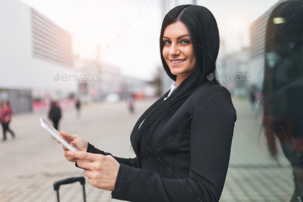 Young business woman with tablet and suitcase in an urban setting